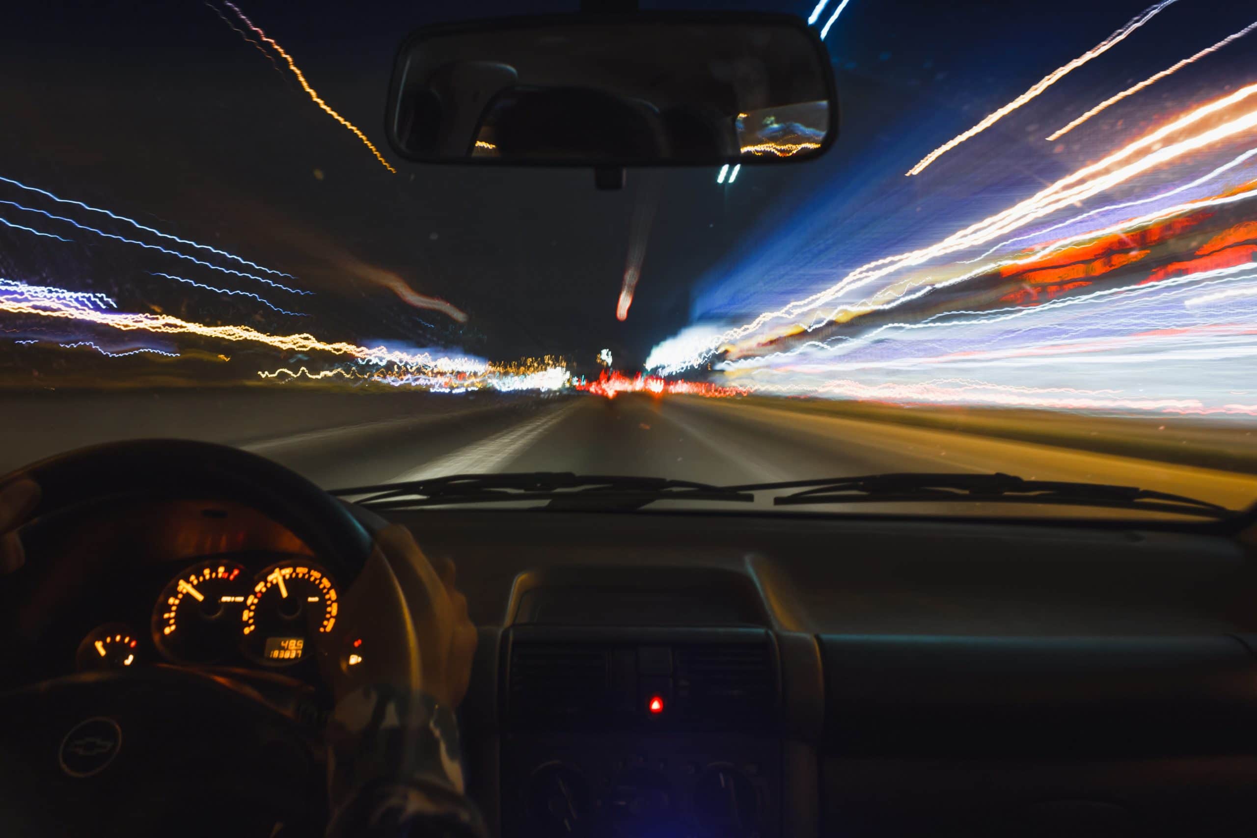 Driver's view of night motorway with light trails representing Plexus Freight's express and time-critical road freight services