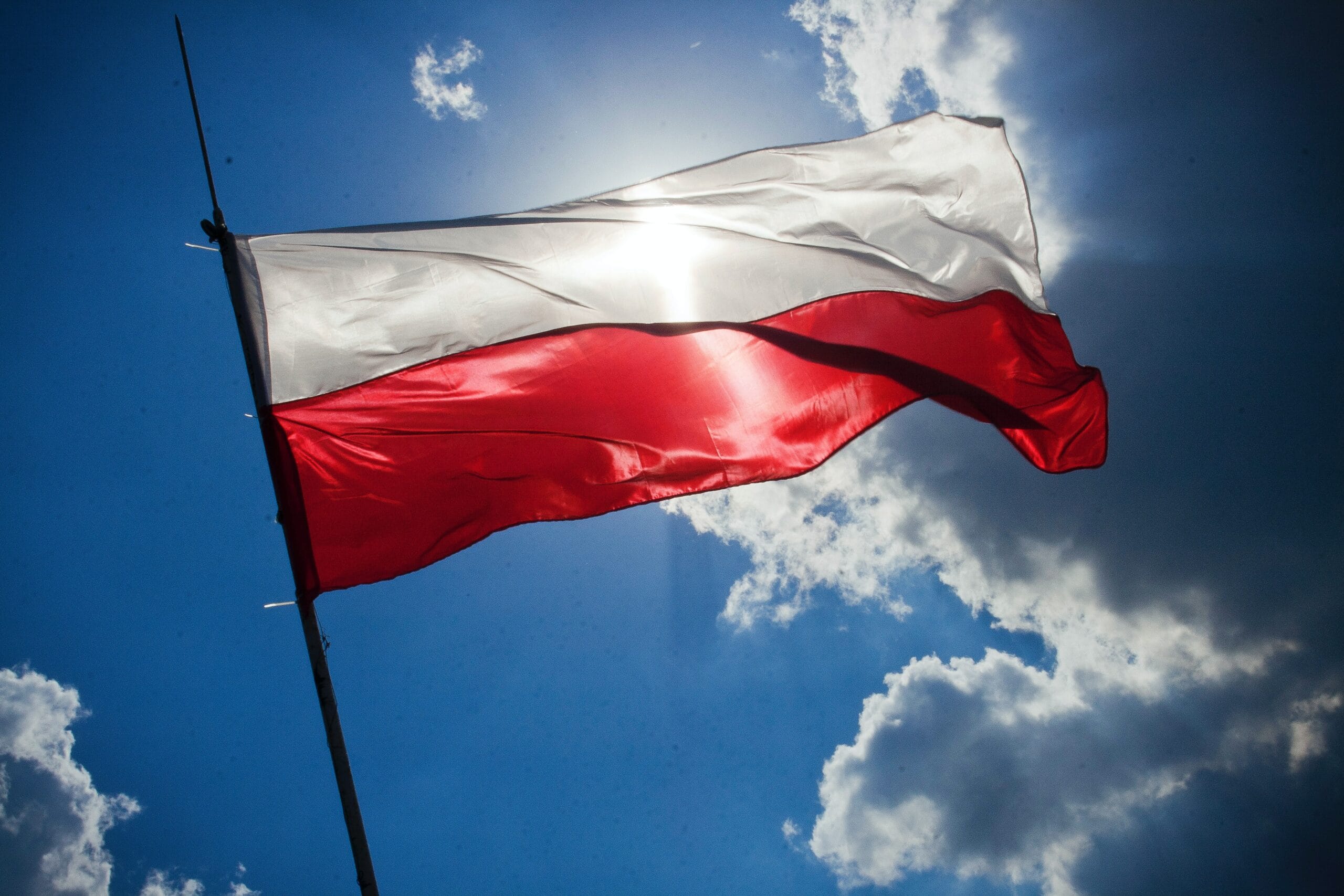 Polish national flag flying against blue sky representing Plexus Freight's Poland road freight services