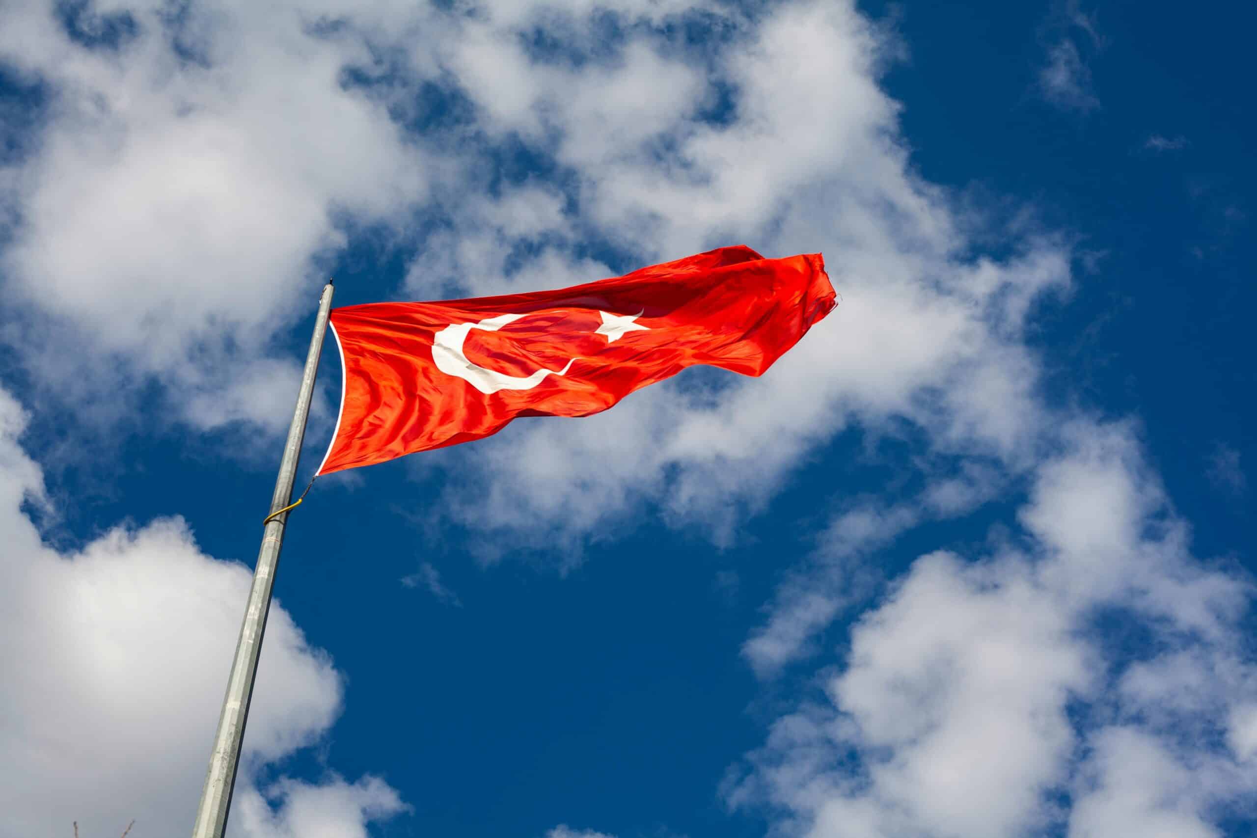 Turkish flag flying against a blue sky with white clouds