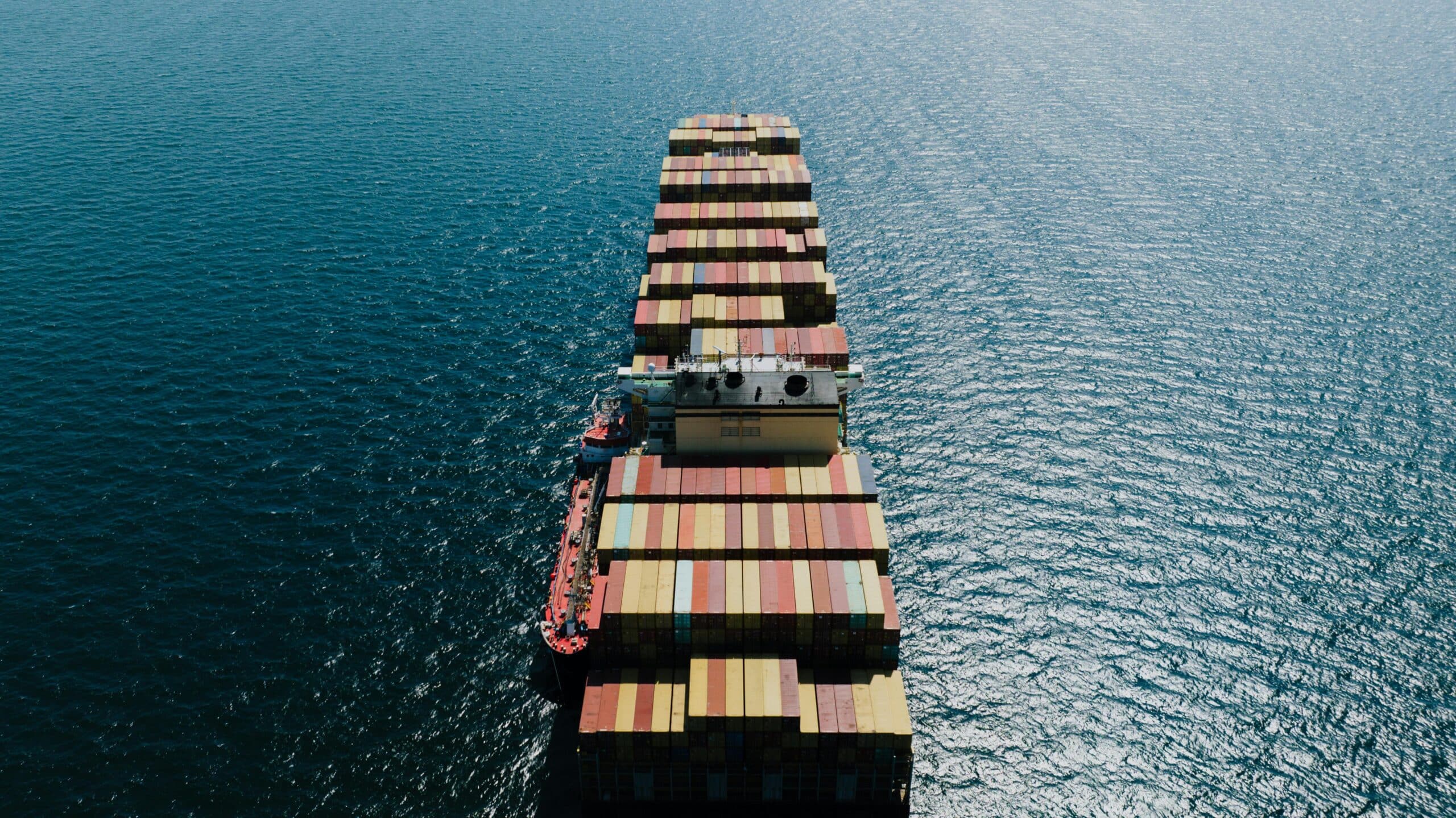 Top-down aerial view of a fully loaded container ship crossing open ocean