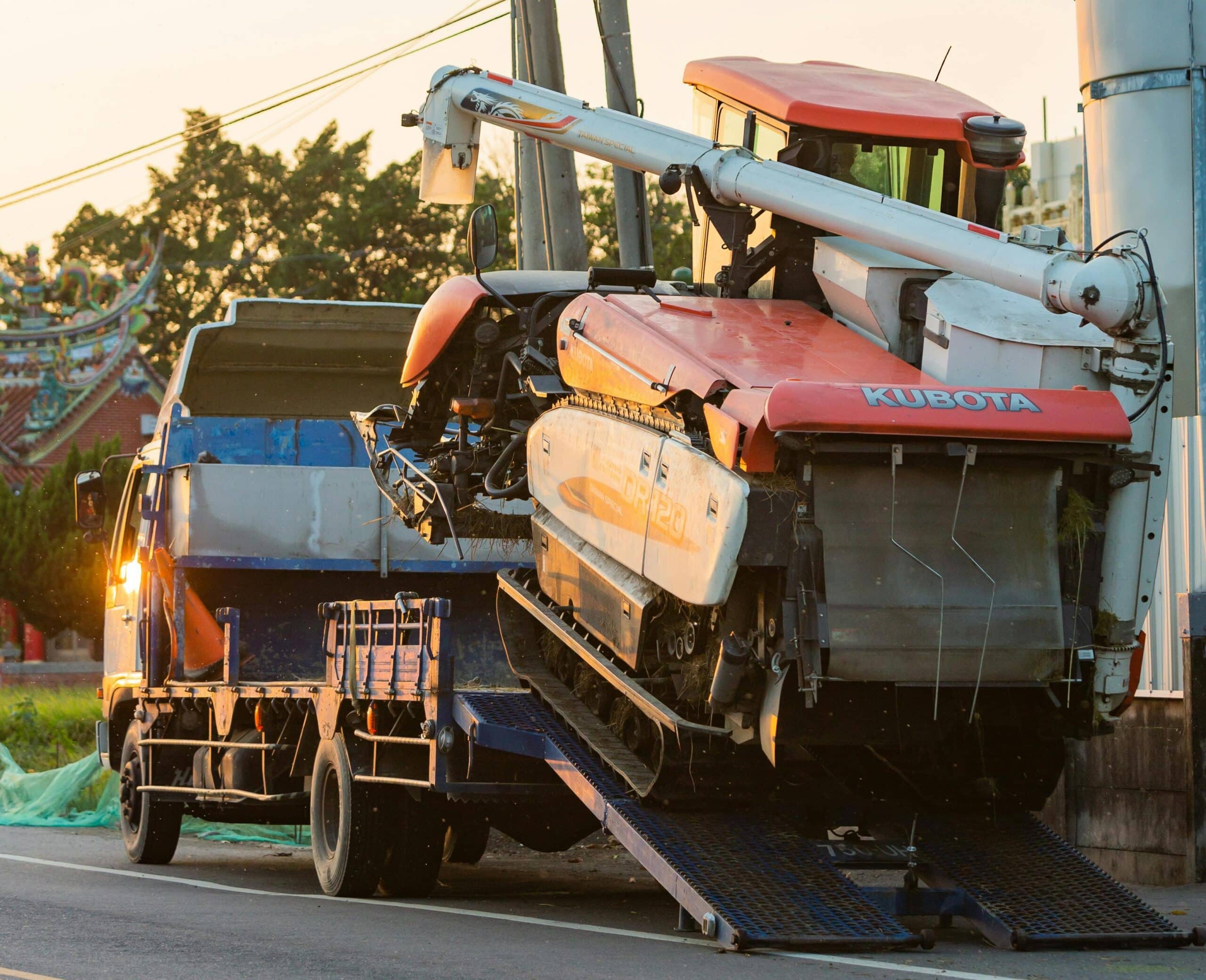 Agricultural harvester being loaded onto a flatbed truck representing Plexus Freight's heavy machinery transport services